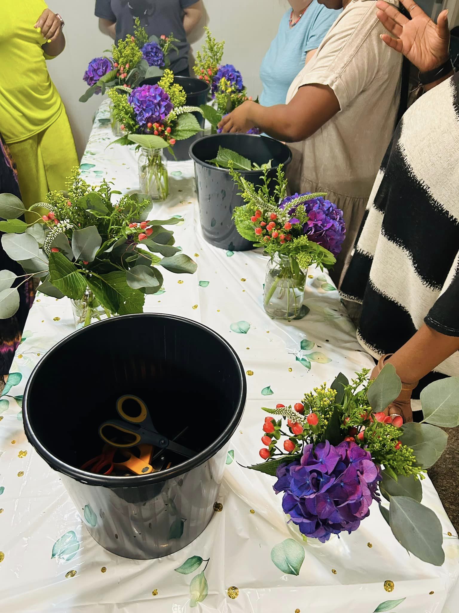 people arranging flowers together around a table